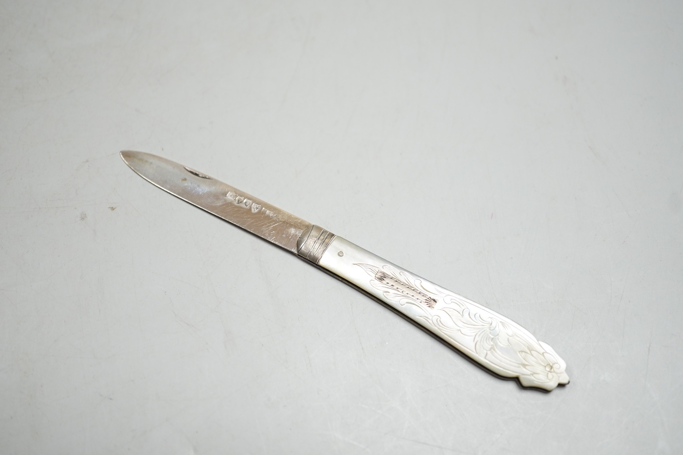A silver tea strainer, a George III silver 'shovel' caddy spoon, London, 1811, a mother of pearl handled silver fruit knife and George IV silver game skewer, London, 1825, 14.7cm.